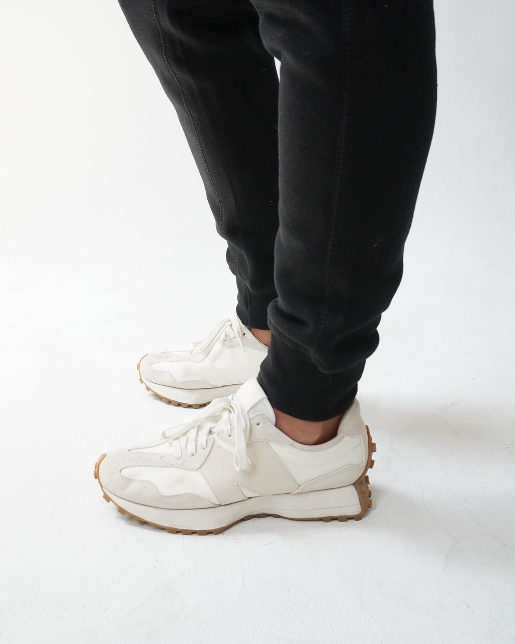 A person wearing off-white chunky sneakers with black pants, standing on a white studio floor.